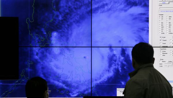 Филиппинские метеорологи смотрят на спутниковое изображение тайфуна Мелор