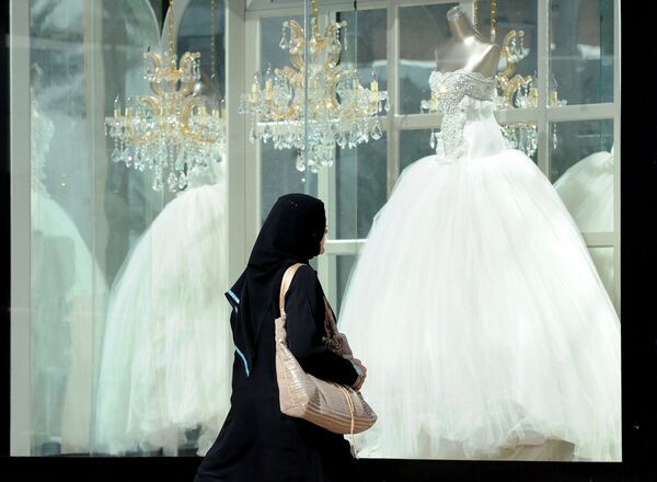 Женщина проходит мимо витрины магазина со свадебными платьями в Саудовской Аравии