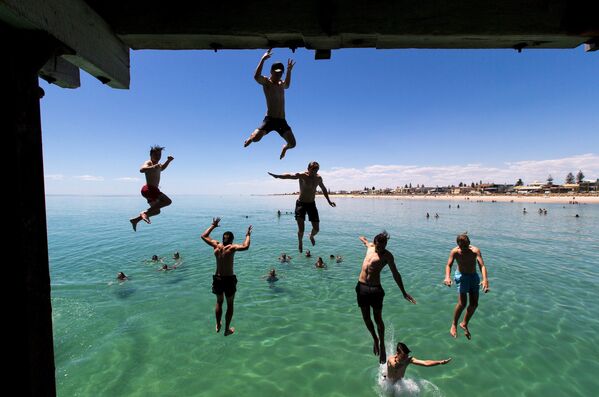 Люди прыгают в воду на пляже Хенли-Бич, Австралия