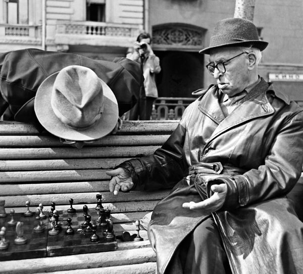 Пенсионеры играют в шахматы на скамейке в сквере. 1969 год