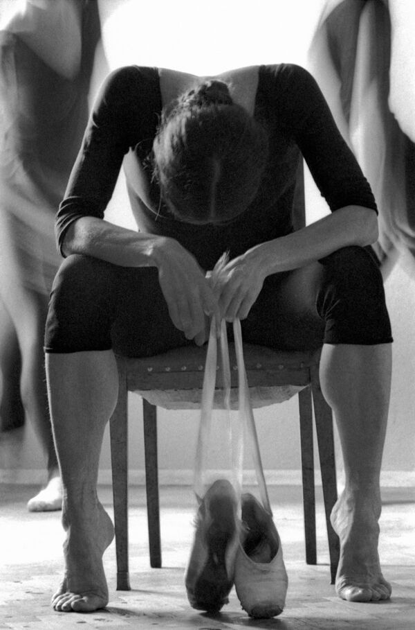 Балерина, сняв пуанты, отдыхает после репетиции, сидя на стуле. 1985 год