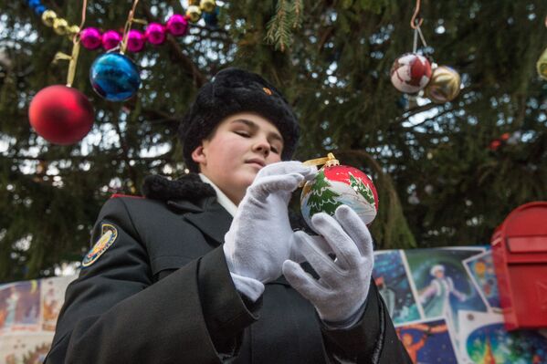 Кадет держит ёлочную игрушку у Новогодней елке на Соборной площади Кремля в Москве