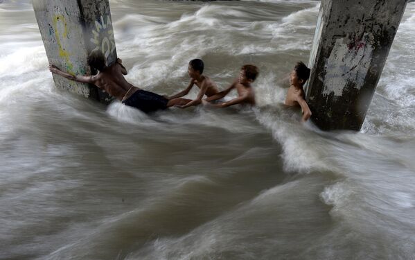 Дети купаются в реке под эстакадой в Маниле, Филиппины