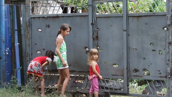 Дети у ворот, поврежденных осколками в результате обстрела украинских силовиков