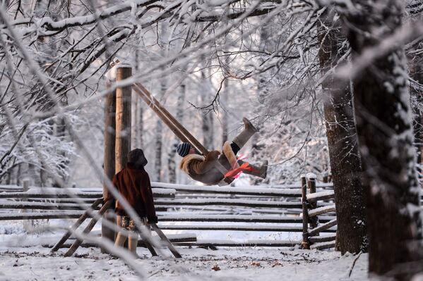 Дети катаются на качелях на зимнем празднике Святок в Музее народного деревянного зодчества Витославлицы