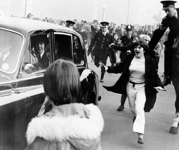 Автомобиль с участниками группы The Beatles в окружении фанатов. Лондон, Англия. 1965 год
