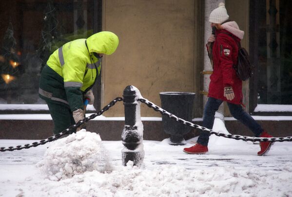 Мужчина убирает снег на Невском проспекте в Санкт-Петербурге