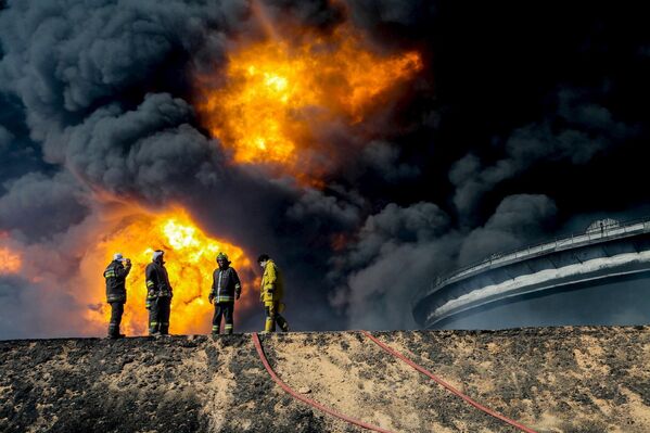 Пожарные возле нефтяного резервуара в городе Эс-Сидер, Ливия