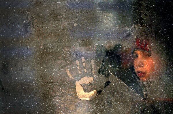 Мальчик смотрит через замерзшее окно автобуса в Минске