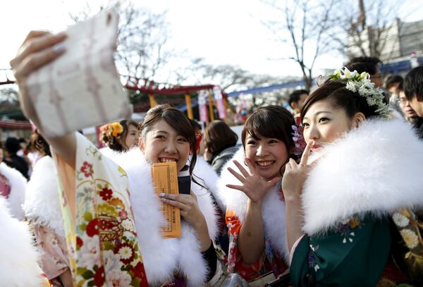 Японские девушки во время торжественной церемонии дня совершеннолетия в парке развлечений в Токио