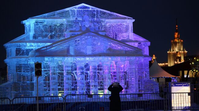 Женщина фотографирует ледяную копию Большого театра на фестивале Ледовая Москва. В кругу семьи в парке Победы 