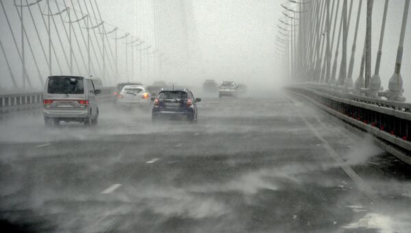 Автомобили едут по вантовому мосту через бухту Золотой Рог во время снежного циклона во Владивостоке