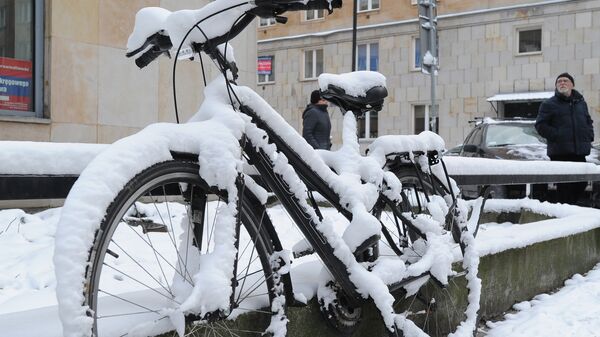 Занесенный снегом велосипед на одной из улиц Варшавы, Польша