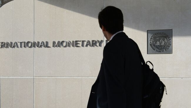 Мужчина у здания Международного валютного фонда смотрит на логотип МВФ на стене. Архивное фото