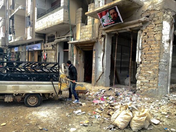 Местный житель принимает участие в восстановительных работах у пострадавшего от теракта жилого дома в квартале аз-Захра в Хомсе в Сирии