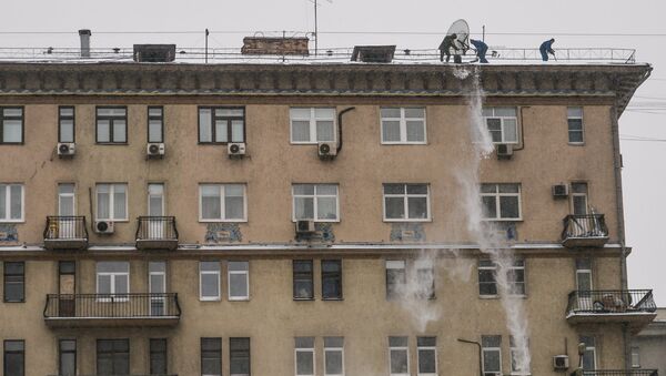 Работники служб ЖКХ сбрасывают снег с крыши одного из домов на Смоленском бульваре в Москве