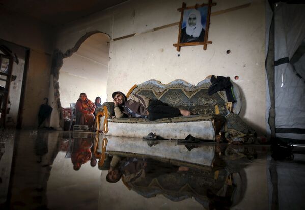 Житель Палестины лежит на диване в своем затопленном после дождя доме, поврежденном в ходе военных действий. Бейт-Ханун, Сектор Газа. Январь 2015