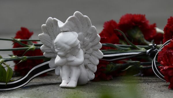 Цветы и фигурка ангела в память о погибших в пожаре в Доме профсоюзов
