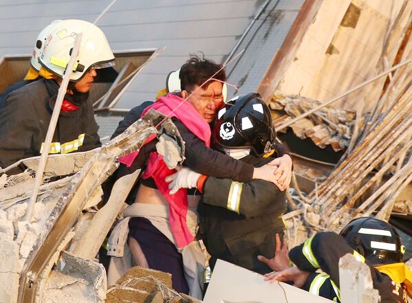 Спасатели помогают мужчине, пострдавшему во время землетрясения на Тайване, 6 февраля 2016