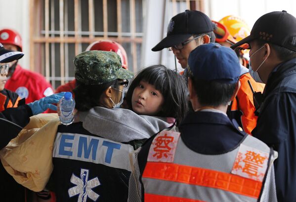 Спасатели помогают ребенку, пострдавшему во время землетрясения на Тайване, 6 февраля 2016
