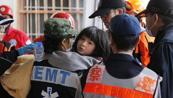 Спасатели помогают ребенку, пострдавшему во время землетрясения на Тайване, 6 февраля 2016
