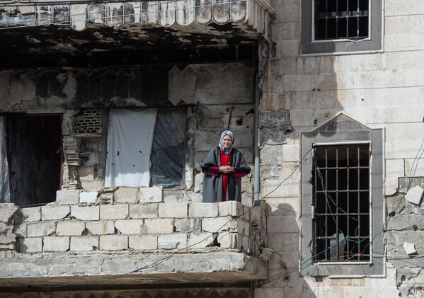 Женщина на балконе здания в районе Хомса Баба Амр