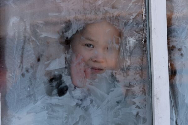 Девочка в окне домика на зимней чабанской стоянке в местечке Чумур-Ой Тес-Хемского кожууна Республики Тыва