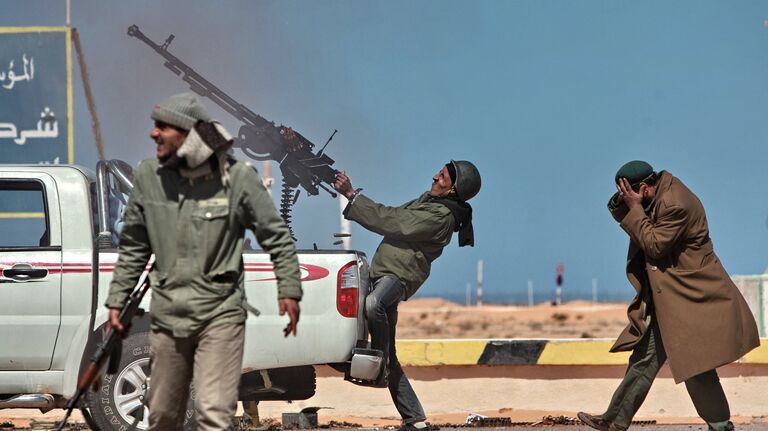 Боец оппозиции стреляет из пулемета по истребителю в городе Рас-Лануф, Ливия. Март 2011