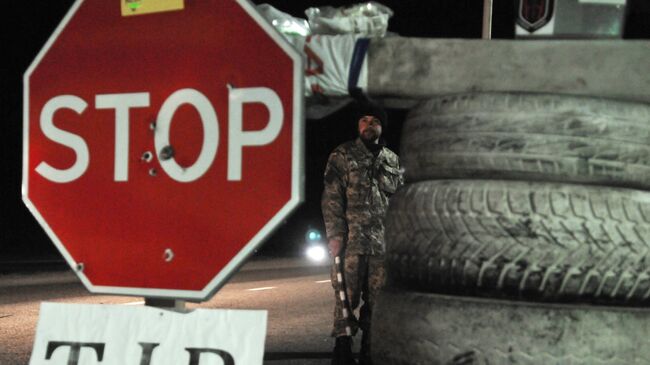 Украинский активист стоит на блокпосту возле Львова, блокируя движение грузовиков с российскими номерами во Львовской области