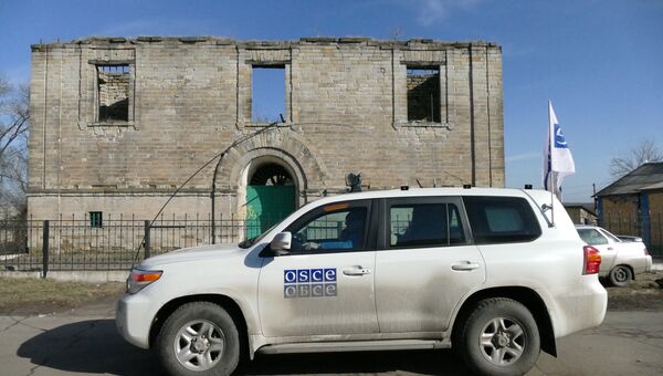 Автомобиль ОБСЕ у разрушенного дома в поселке Зайцево. Архивное фото