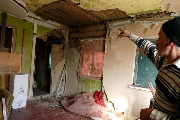 Местный житель у разрушенного дома в поселке Зайцево в Донецкой области