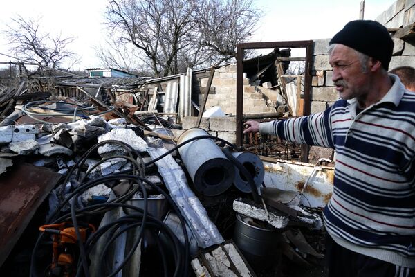 Местный житель у разрушенного дома в поселке Зайцево в Донецкой области
