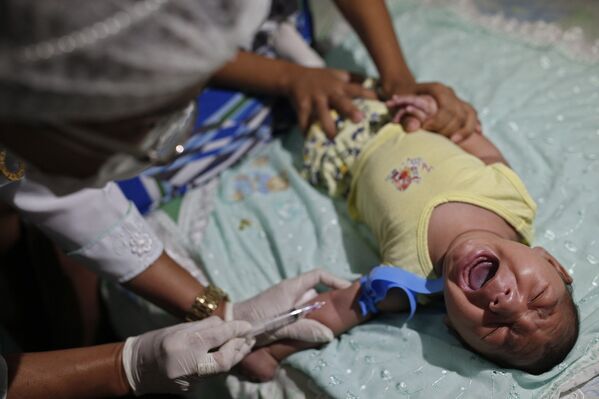Врач берет кровь у младенца с микроцефалией в Жуан-Песоа, Бразилия
