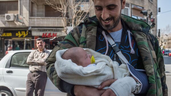 Мужчина с грудным ребенком на улице Дамаска в первый день перемирия. Архивное фото