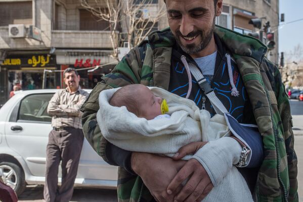 Мужчина с грудным ребенком на улице Дамаска в первый день перемирия