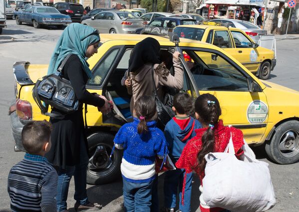 Женщины с детьми садятся в такси на одной из улиц Дамаска в первый день перемирия