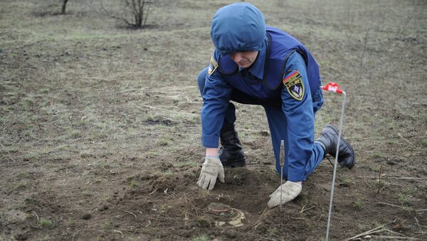Сотрудник МЧС ДНР раскапывает мину. Архивное фото