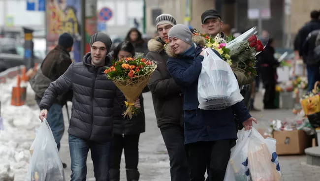 Мужчины с букетами цветов в преддверии праздника 8 марта в Москве