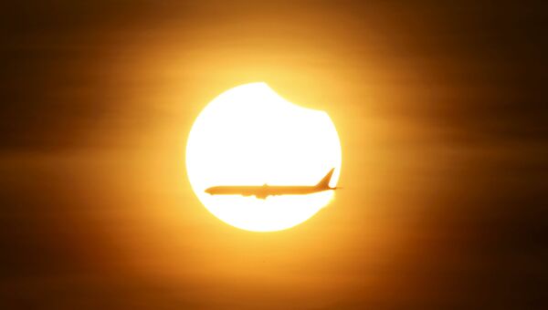 Самолет на фоне солнца в момент частичного солнечного затмения в Сингапуре, 9 марта 2016