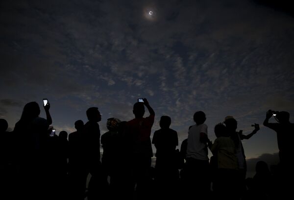 Люди наблюдают за солнечным затмением в Индонезии, 9 марта 2016