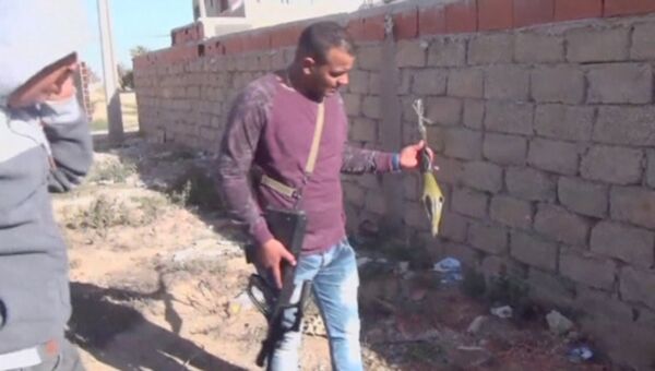 Сотрудники полиции держат гранатомет, найденный на месте нападения боевиков ИГИЛ на город Бен-Гардан, Тунис