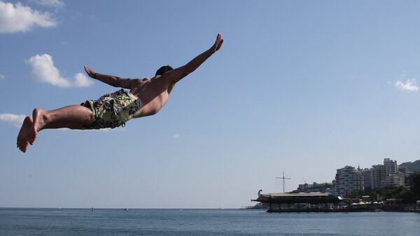 Мужчина прыгает в море на пляже в Ялте. Архивное фото