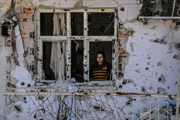Женщина в окне разрушенного дома в Джизре, Турция. Март 2016