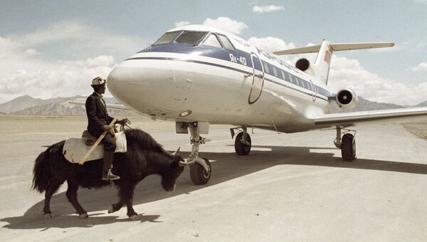 Житель Таджикистана проезжает верхом на горном яке мимо самолета ЯК-40. Архивное фото