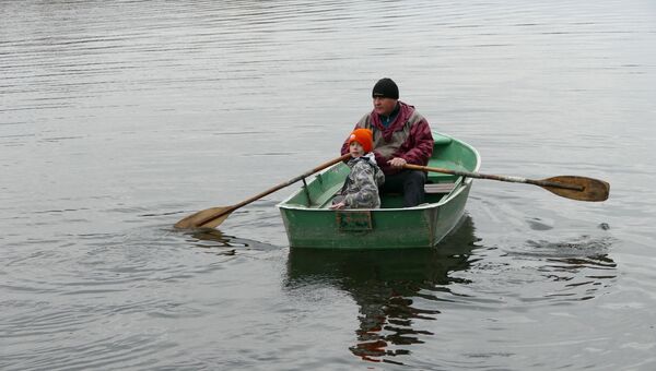 Мужчина катает ребенка на лодке в Донецке. Архивное фото