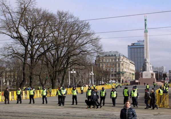 Сотрудники полиции стоят в оцеплении на площади перед памятником Отечеству и свободе в Риге - конечной точке маршрута шествия латышского легиона Ваффен СС