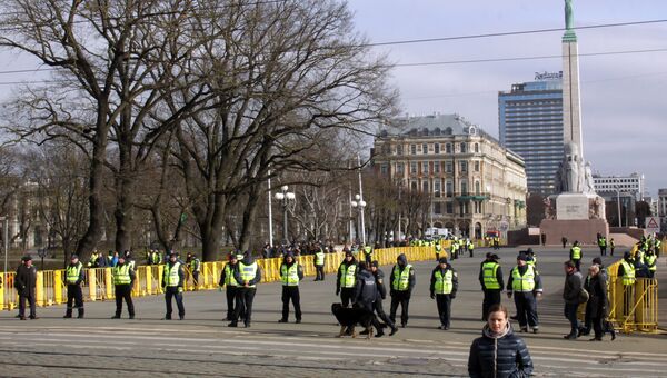 Сотрудники полиции стоят в оцеплении на площади перед памятником Отечеству и свободе в Риге - конечной точке маршрута шествия латышского легиона Ваффен СС