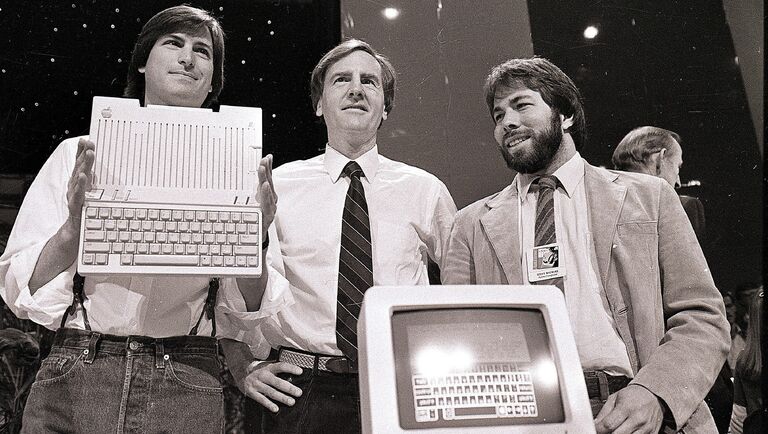 Стив Джобс, Джон Скалли и Стив Возняк во время презентации нового компьютера компании Apple в Сан-Франциско, США. 24 апреля 1984