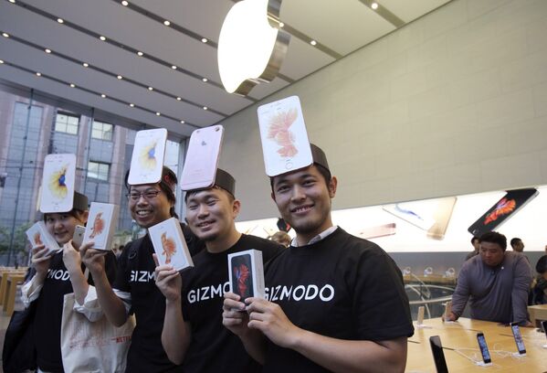 Покупатели в магазине Apple store в Токио демонстрируют только что приобретенные смартфоны iPhone 6s компании Apple
