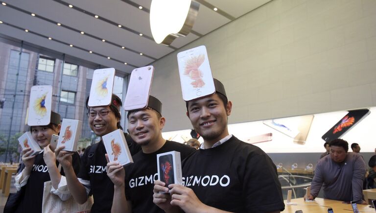 Покупатели в магазине Apple store в Токио демонстрируют только что приобретенные смартфоны iPhone 6s компании Apple